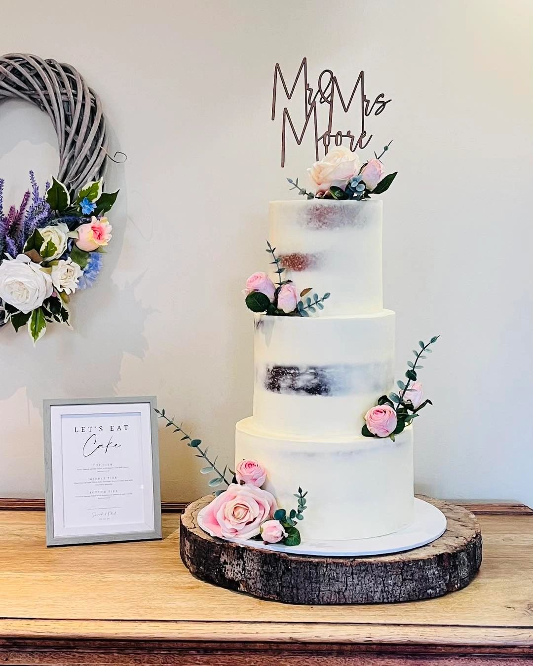 Elegant three-tier wedding cake with pink floral decorations.