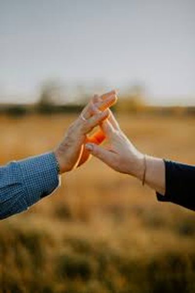 Two hands gently touching against a blurred outdoor background.