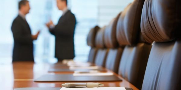 Conference room with two businessmen talking in the background.