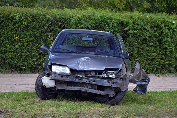 Damaged car with crushed front and detached bumper on grass in lancaster tx.