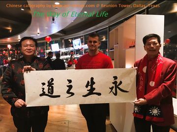 Three men hold a Chinese calligraphy banner in a modern indoor setting.
