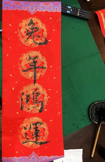 Traditional Chinese calligraphy on red paper with gold accents.