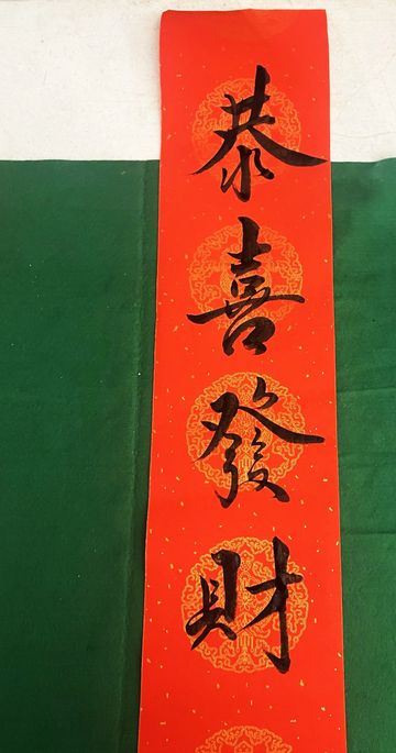 Chinese calligraphy on a red scroll with golden patterns.