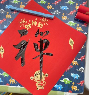 Chinese calligraphy on red paper with festive decorations.
