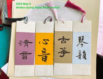 Four colorful bookmarks with Chinese calligraphy and tassels laid on a table.