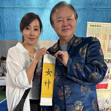 Two people holding a decorative scroll with Chinese characters.