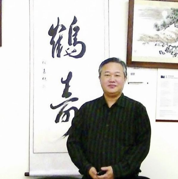 Man standing in front of a wall with Asian calligraphy and art.