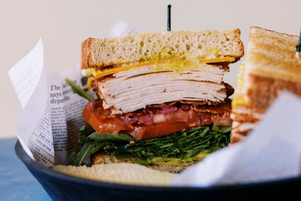 Close-up of a hearty turkey sandwich with lettuce, tomato, and mustard.