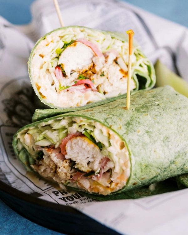 Close-up of a chicken wrap cut in half with green tortilla.
