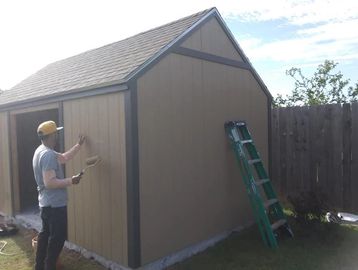 Painting a storage shed built by Outdoors Construction.