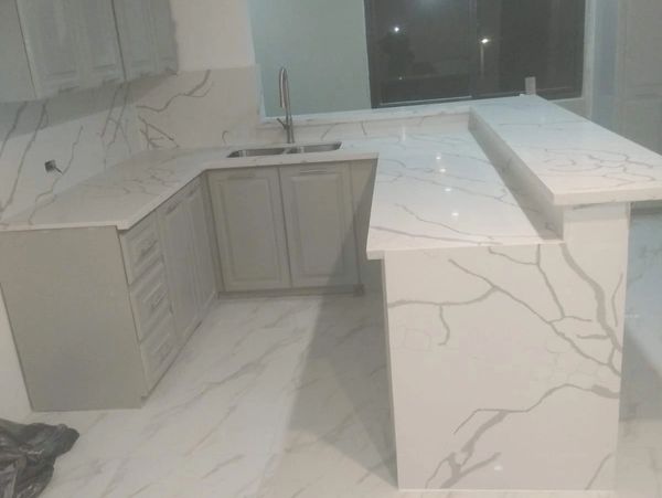 Modern kitchen with white marble countertops and flooring.