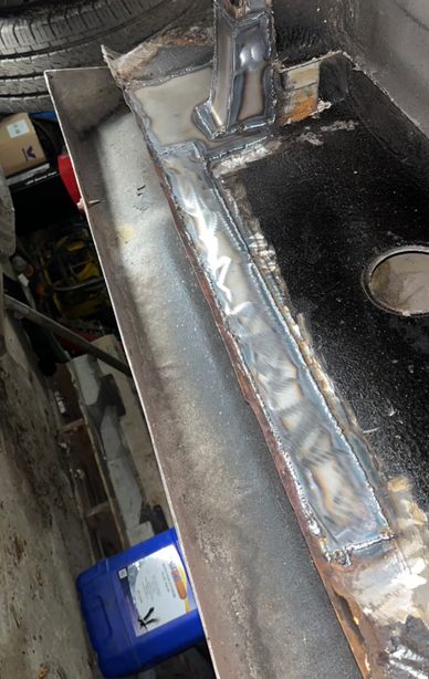 Close-up of a welded metal piece with weld beads and a hole.