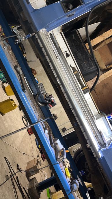 Blue vehicle on a lift with tools scattered around in a garage.