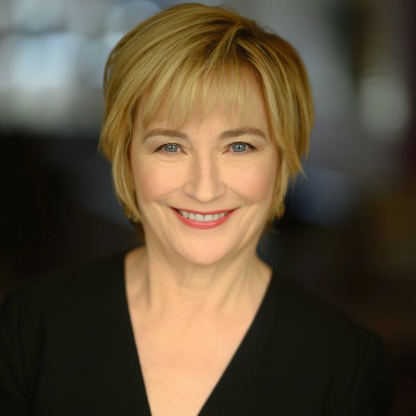 Smiling middle-aged woman with short blonde hair and blue eyes in a black top.