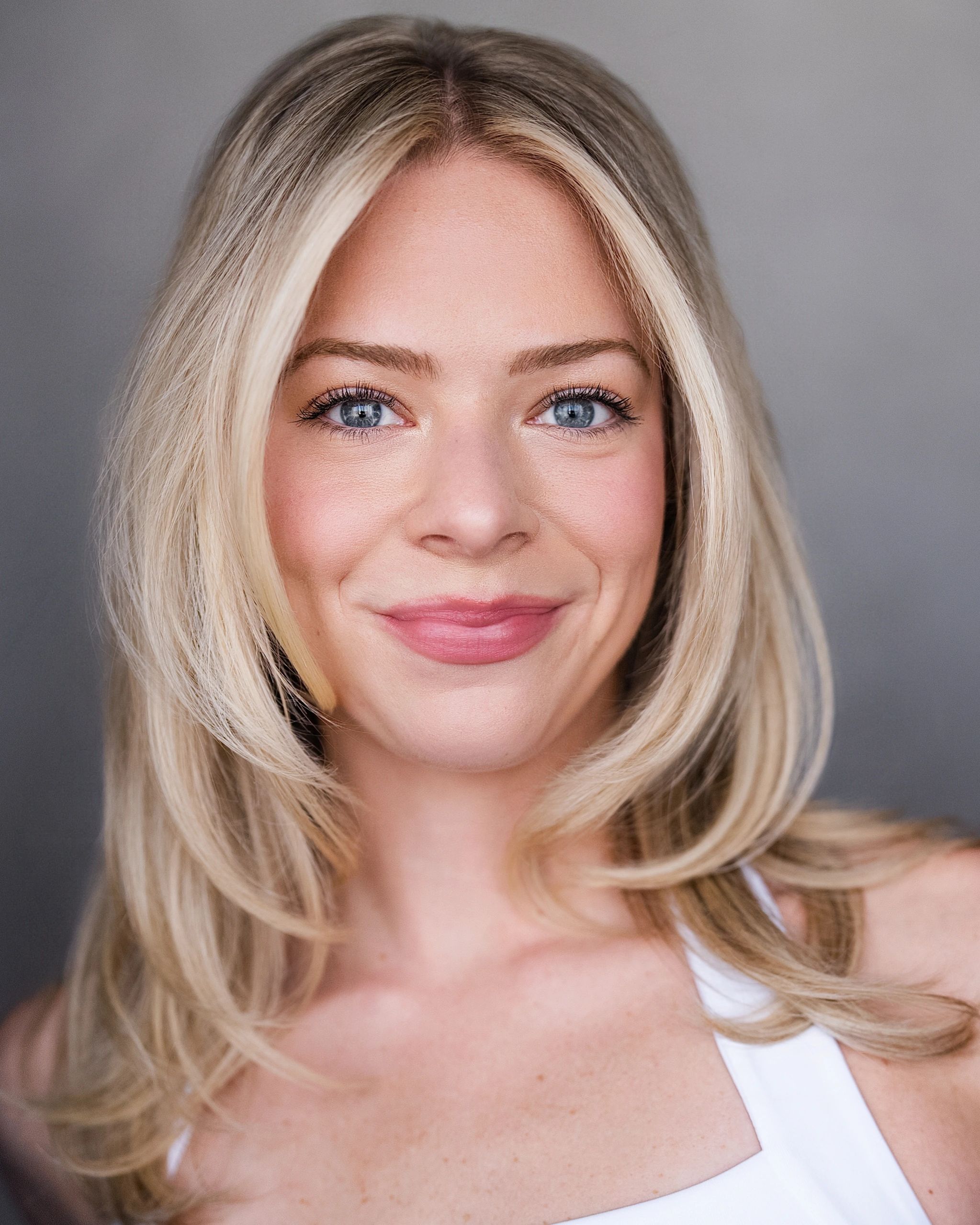 Close-up portrait of a smiling blonde woman with blue eyes.