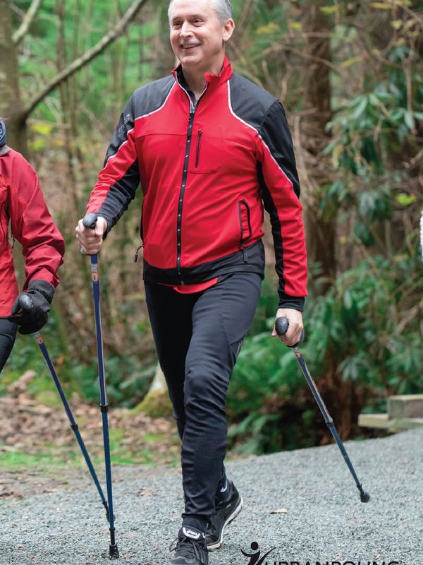 White male striding quickly with good posture in group walk in forest with Nordic  or Urban poles