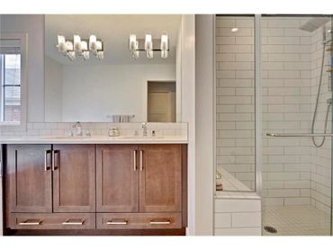 Modern bathroom with double vanity and glass-enclosed shower.
