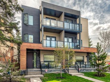 Modern three-story residential building with balconies and mixed materials.
