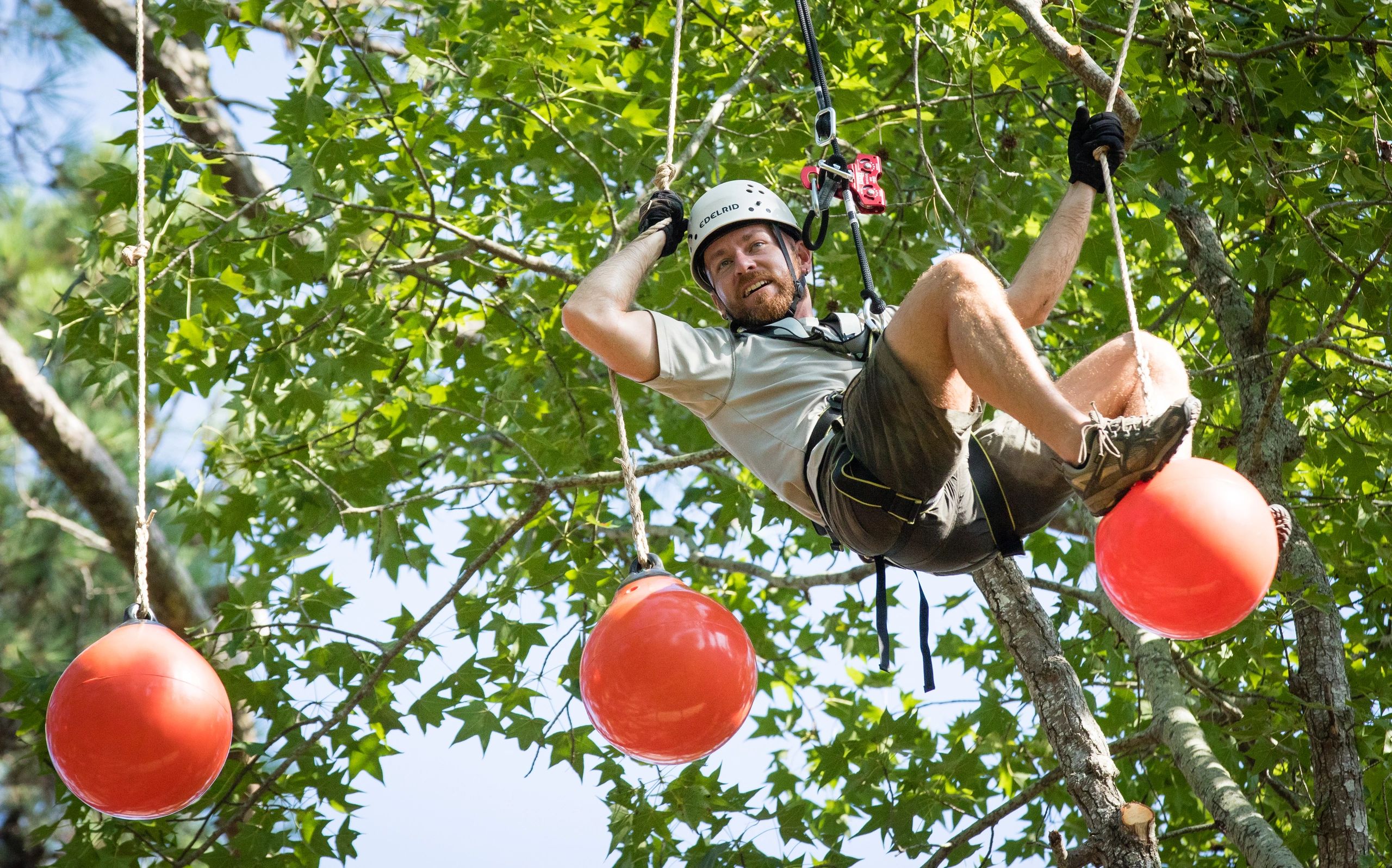 Man on challenge course activity on outdoor ropes course in Wisconsin.