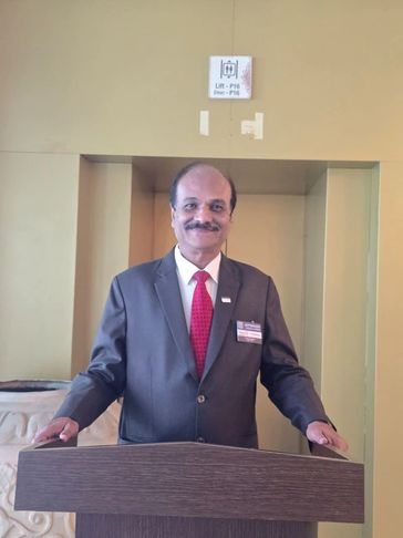 Man in suit standing behind a podium, smiling.