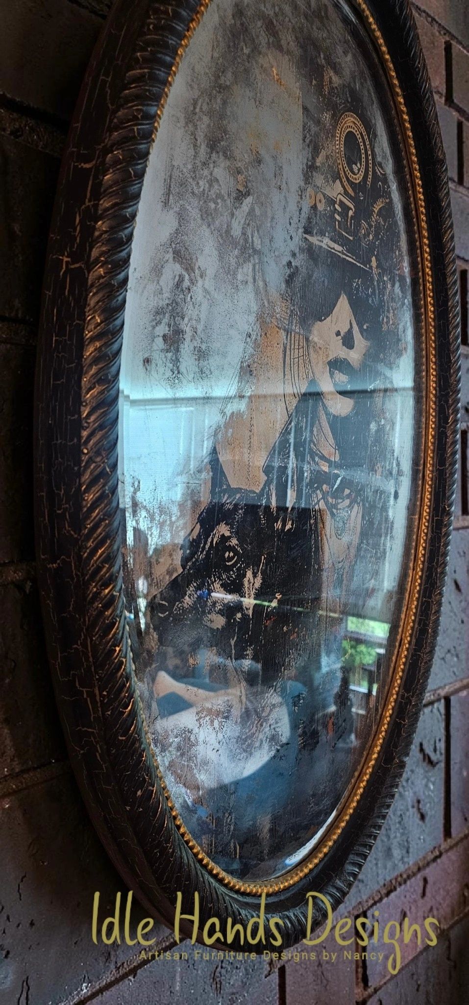 Oval vintage mirror with etched art of a woman and a dog in an ornate frame.