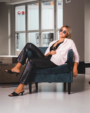 Fashion photography of a confident woman in chic outfit posing indoors with stylish sunglasses.


