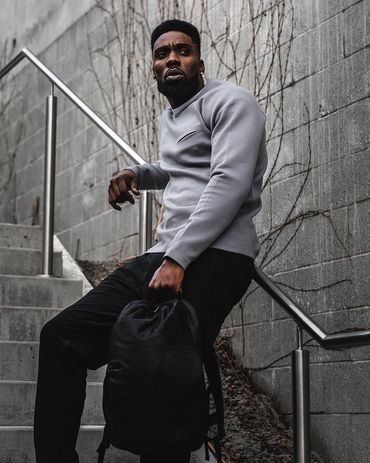 Urban lifestyle photo of a stylish man in casual wear posing confidently with a backpack.