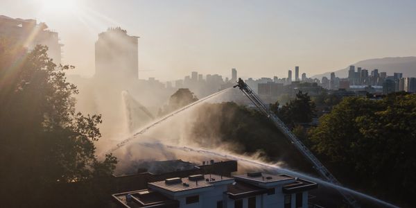 cinematic photography of VFRS fireman using hose and ladder to put out apartment fire in vancouver