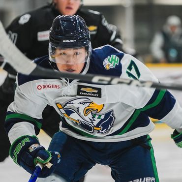 korean born british columbia hockey league player skating along the boards with the puck