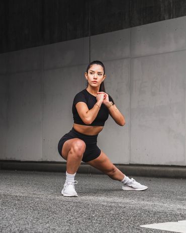 fitness photography of gym girl performing side lunges against a concrete wall.