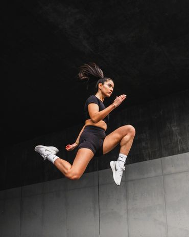 fitness photography of a gym girl jumping in a tunnel against a concrete wall