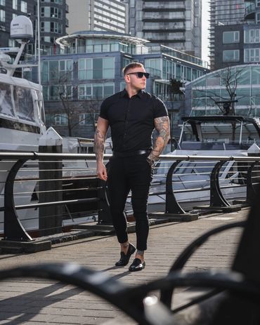 Fashion photography of a stylish man in black outfit posing confidently by the marina
