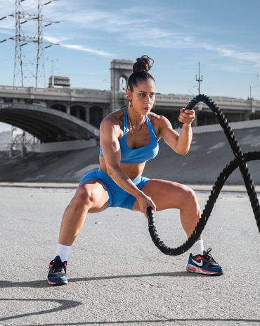 fitness photography of a woman in a blue athleticwear set exercising with battle ropes in the LA Riv