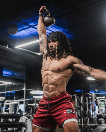 Male fitness athlete performing kettlebell snatch inside a dark gym