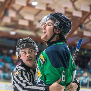 hockey player chirping while being held back by referee