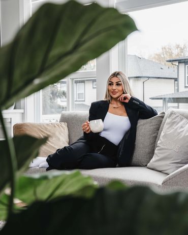 Lifestyle realtor photography of a woman relaxing on a couch with coffee in a bright modern home.