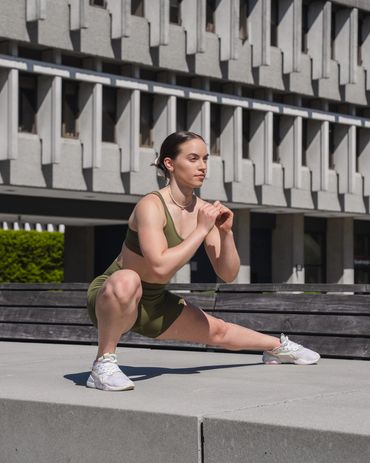 athletic fitness girl performing a side lunge in front of concrete building in British Columbia