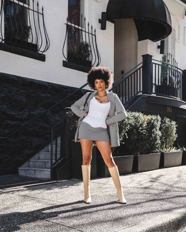 fashion photography of a stylish woman with afro, boots, and skirt posing in front of chic hotel.