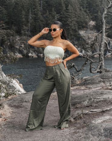 Fashion photography of a stylish woman posing outdoors by the ocean in chic summer outfit.