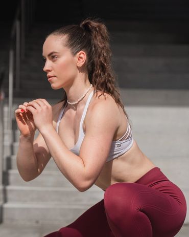 fitness photography of a woman doing a side lunge, wearing red leggings and white sports bra