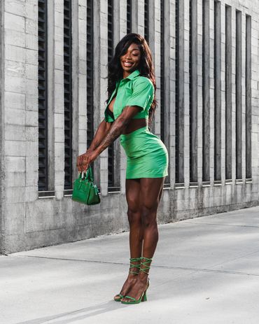 Fashion photography of a confident woman in green outfit posing stylishly in an urban setting.
