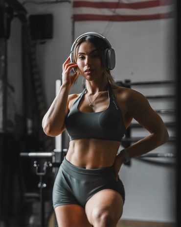 Fitness photography of a woman in gym wear with headphones, focused during workout session.