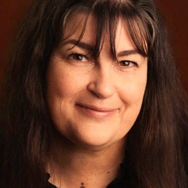 Close-up portrait of a smiling woman with long dark hair and bangs.