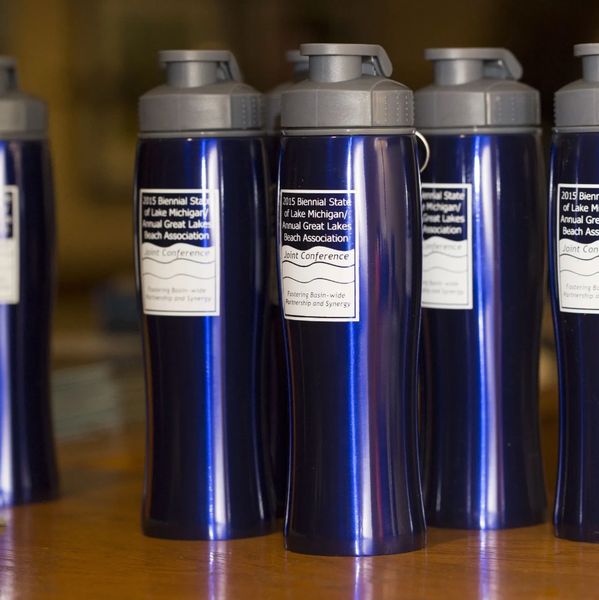 Blue water bottles with conference labels lined up on a table.