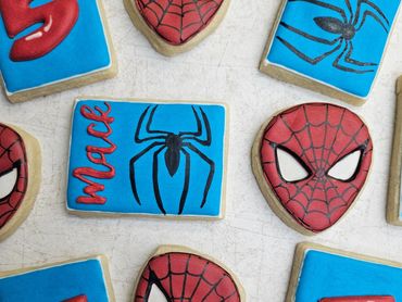 Spider-Man themed decorated cookies with red, blue, and black icing.