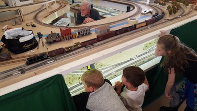 Children watch a detailed model train set with an older man.