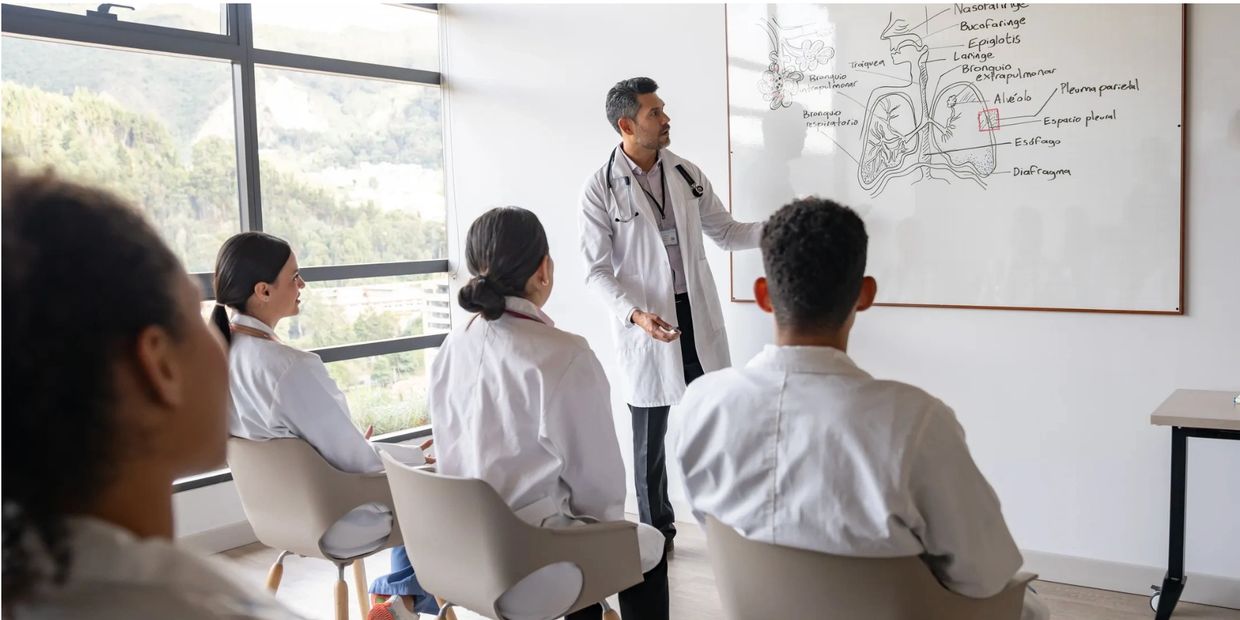 Medical instructor teaching students about the respiratory system on a whiteboard.