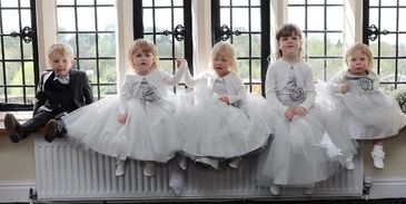 SARAH BELLE FLOWER GIRLS SAT ON WINDOW SILL WEARING FLOWER GIRL DRESSES IN SILVER AND IVORY