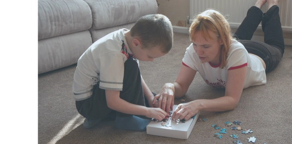 a mother helping her autistic child play with a puzzle through her aba therapy training