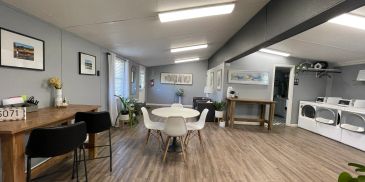 Community room with tables, chairs, and laundry machines.